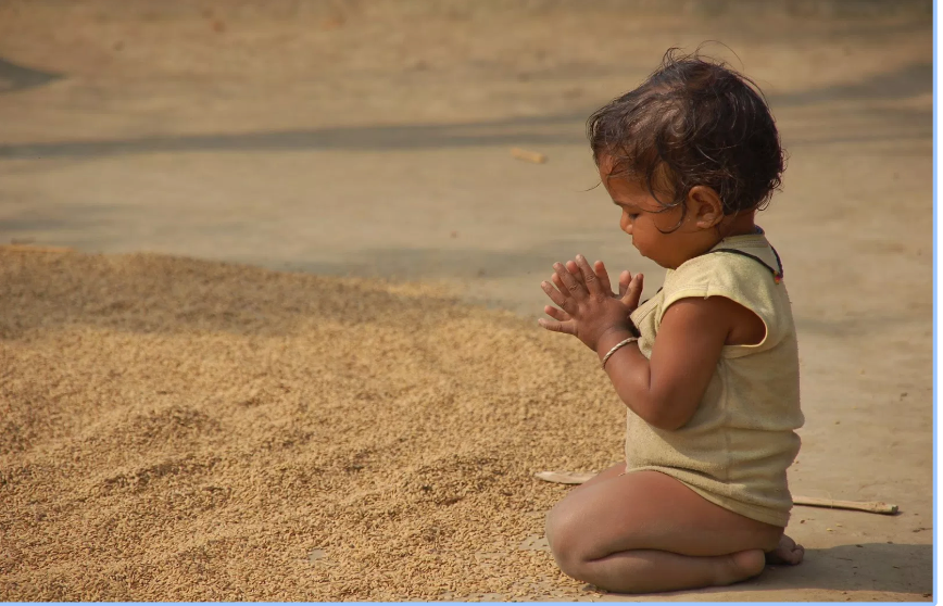 Child praying on the sand 