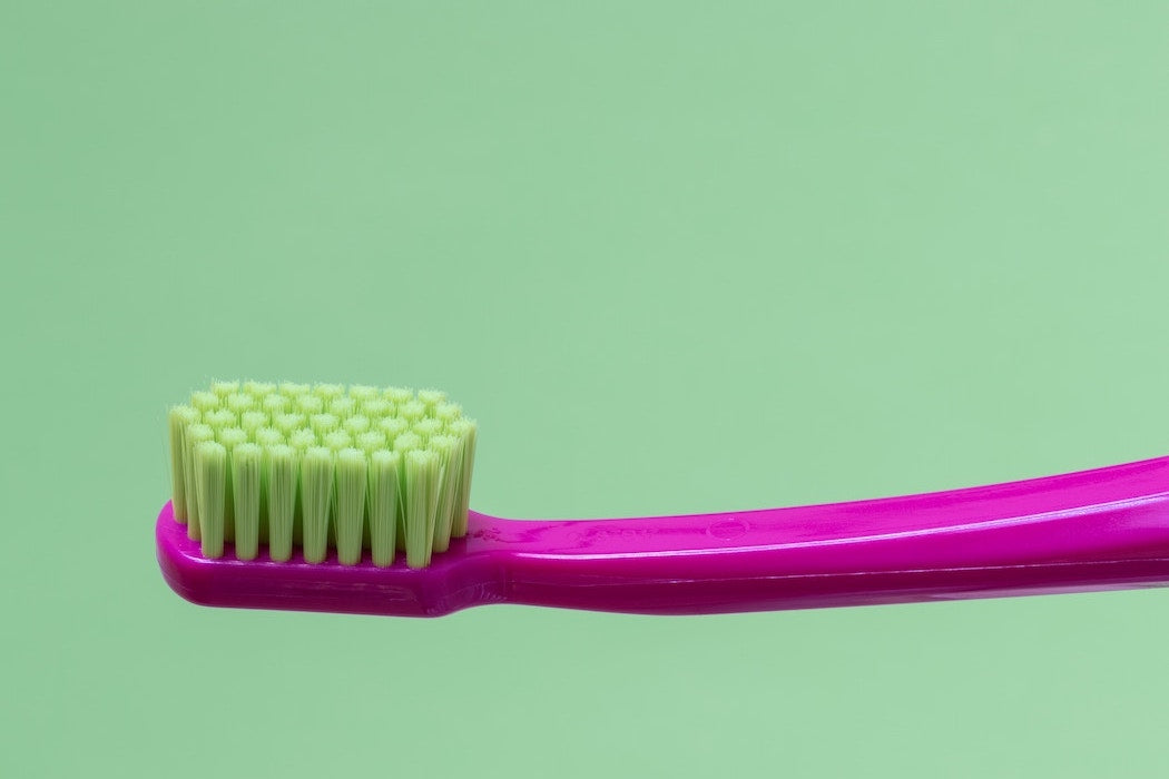 Pink tooth brush on green background